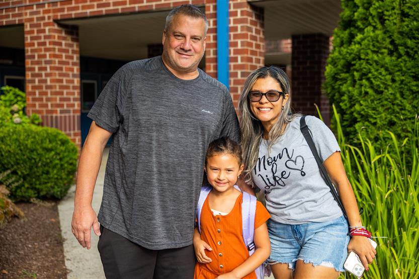 A family of three smiles at Bethesda Elementary